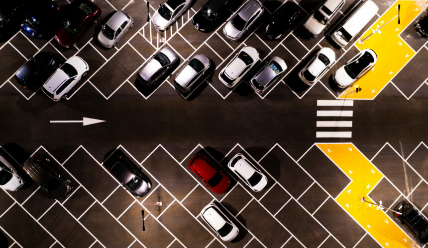 Drone aerial view of parking lots with cars at night. Crowded shopping mall outdoors car park.